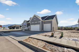 Modern farmhouse with a mountain view, board and batten siding, concrete driveway, and an attached garage