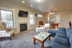 Living room with a chandelier, carpet floors, a tile fireplace, and recessed lighting