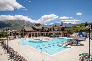 Community pool with a water play area, a water slide, a mountain view, a patio area, and a balcony