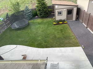 Fenced backyard with a trampoline and a storage unit