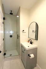 Full bathroom featuring a stall shower, vanity, and light tile patterned floors