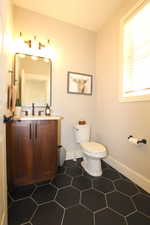 Half bathroom with vanity and dark tile patterned floors