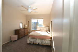 Bedroom with dark colored carpet and a ceiling fan