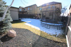 Fenced backyard with a trampoline and a patio