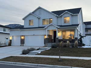 View of front facade with driveway, board and batten siding, and a porch