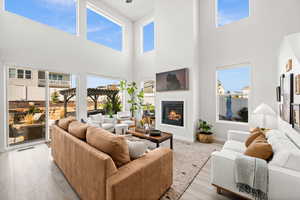Living area featuring a glass covered fireplace, a high ceiling, and light wood-style floors