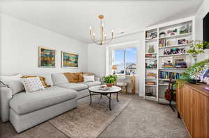 Living room with light colored carpet, a chandelier, and built in features