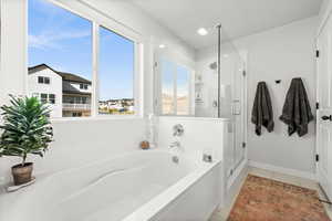 Masterbathroom with a garden tub, a stall shower, and light tile patterned flooring