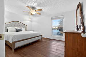 Bedroom with dark wood finished floors, a ceiling fan, and a textured ceiling