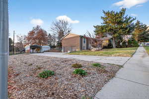 View of property exterior featuring concrete driveway and a detached carport