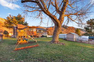 Fenced backyard featuring a playground and an outbuilding