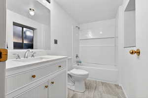 Bathroom with vanity, a textured wall, and tub / shower combination