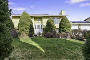 Raised ranch with a front lawn and a chimney