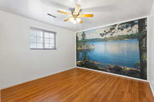 Spare room featuring wood finished floors, a ceiling fan, and a water view