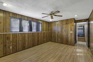 Spare room with wood walls, wood finished floors, ceiling fan, a textured ceiling, and recessed lighting