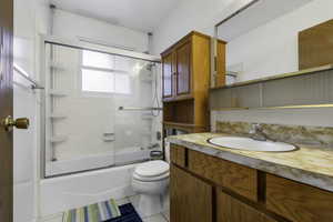 Bathroom with vanity, bath / shower combo with glass door, and light tile patterned floors