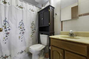 Bathroom with vanity, a shower with curtain, and tile walls