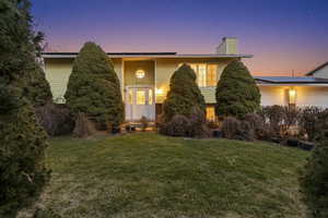 Split foyer home with solar panels, a lawn, a chimney, and an attached garage