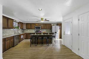 Kitchen featuring a breakfast bar, stainless steel appliances, light wood-type flooring, a center island, and recessed lighting