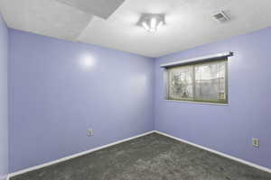 Spare room with a textured ceiling and dark carpet