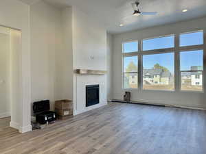 Unfurnished living room featuring a fireplace, wood finished floors, a ceiling fan, and recessed lighting