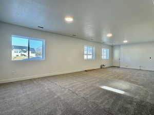 Carpeted spare room featuring a textured ceiling and baseboards