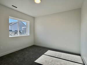 Unfurnished room with dark carpet and baseboards