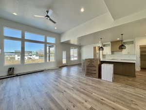 Kitchen with open floor plan, hanging light fixtures, white cabinetry, light wood-type flooring, and light countertops