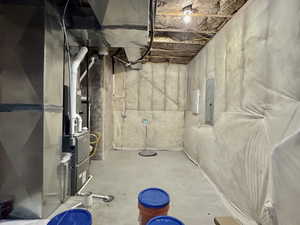 Unfinished below grade area featuring heating unit and electric panel
