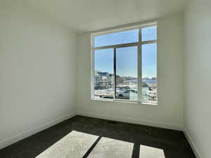 Spare room featuring baseboards and dark colored carpet