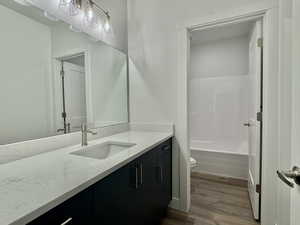 Bathroom with vanity, dark wood-style flooring, and shower / bath combination