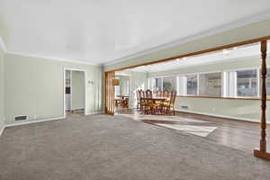 Carpeted living room with ornamental molding and baseboards