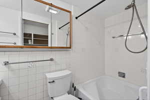 Bathroom featuring tub / shower combination and tile walls