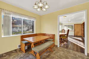 Dining area with stone finish floors, plenty of natural light, a chandelier, and ornamental molding