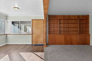 Unfurnished living room with crown molding and wood finished floors