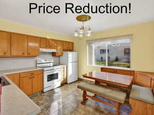 Kitchen with white appliances, light countertops, hanging lights, and wood finish cabinets