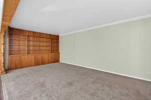 Carpeted room with built in shelves and baseboards