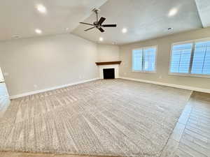 Spacious great room with a gas fireplace, recessed lighting, ceiling fan, light colored carpet, and a textured ceiling