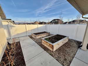 Fenced backyard featuring raised box gardens