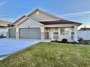 View of front of house featuring board and batten siding, brick, driveway, an attached garage, and a covered porch