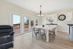 Dining area featuring light wood-style floors, a chandelier, and french doors