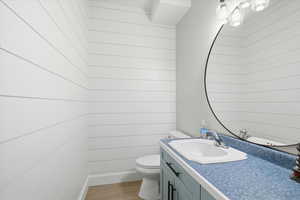 Bathroom featuring vanity, light wood-type flooring, and wood walls