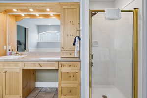 Bathroom with vanity, a shower stall, stone tile floors, and recessed lighting