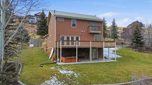 Rear view of house with a hot tub, a yard, a patio, and a deck