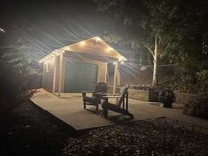 Patio at night with an outbuilding and a garage