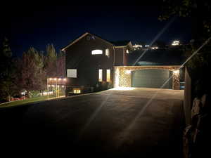 View of front of house with driveway, stone siding, and a garage