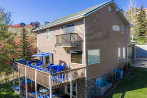 Back of house featuring outdoor dining area, a wooden deck, a patio area, a metal roof, and a lawn