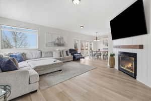 Living area with a glass covered fireplace, light wood-style flooring, and a chandelier