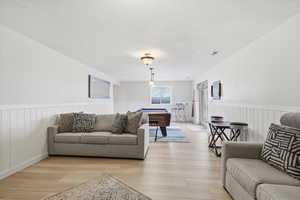 Living area featuring billiards table, a wainscoted wall, and light wood finished floors