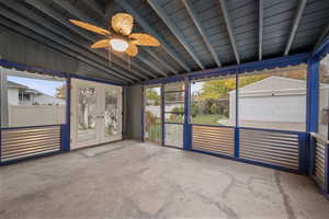 Unfurnished sunroom featuring french doors, lofted ceiling, a ceiling fan, and plenty of natural light